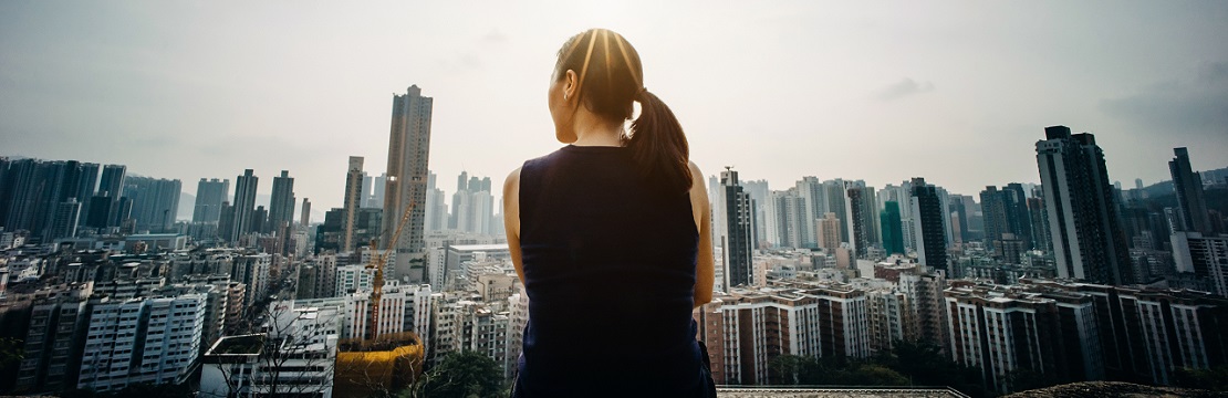 Woman overlooking a cityscape in the sunshine.